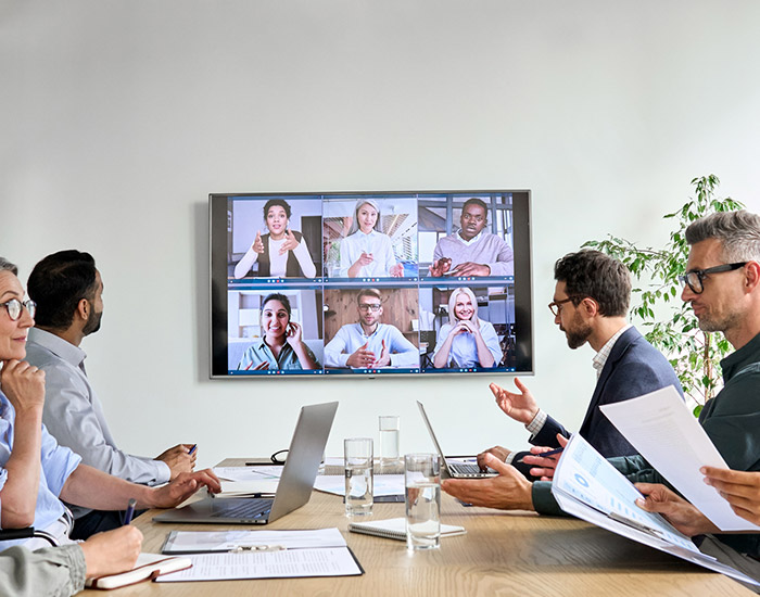Diverse employees on online conference video call on tv screen in meeting room